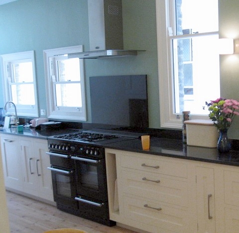 Long galley kitchen with white cabinets and black counter top